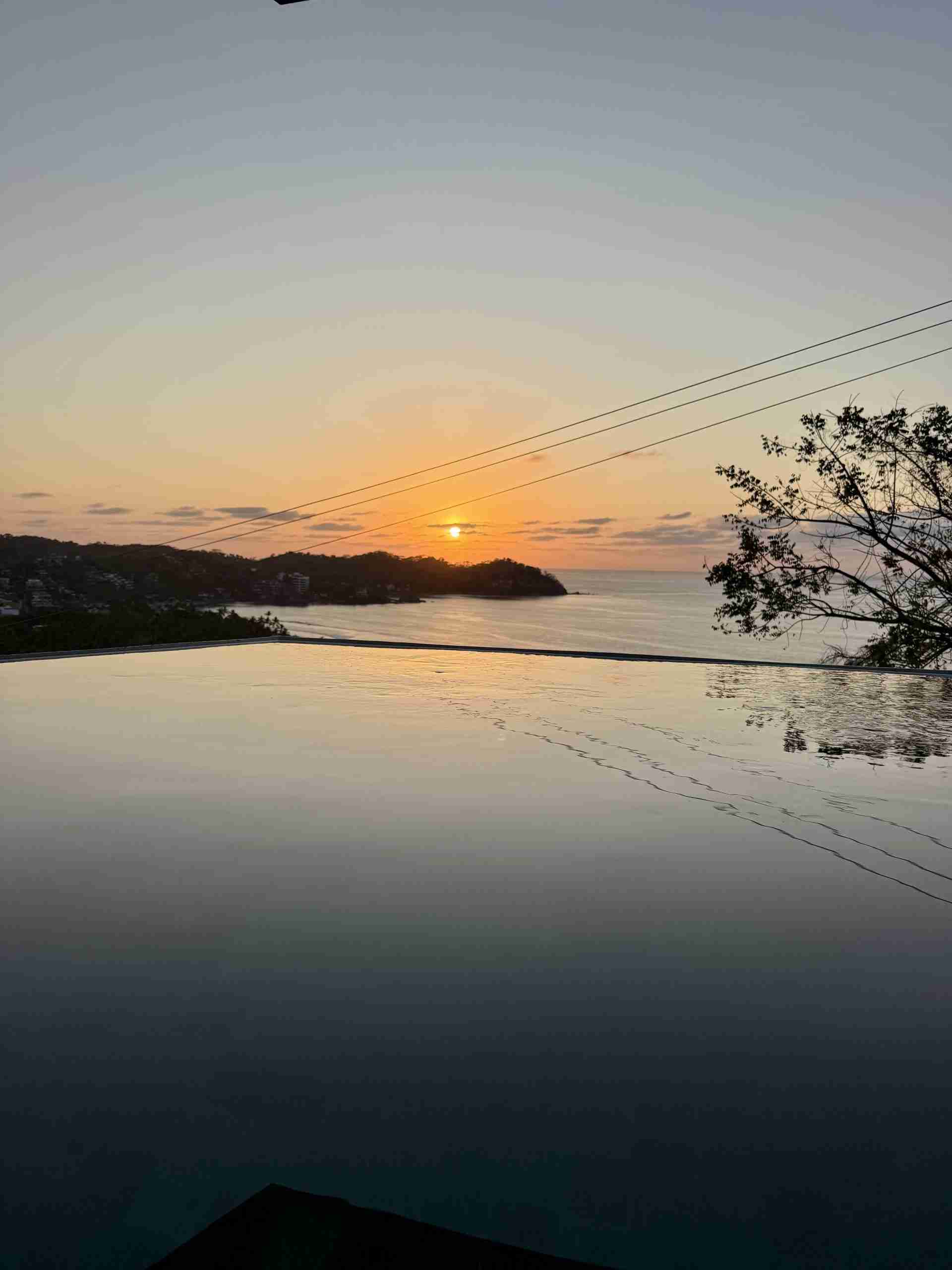 Ocean-facing rooftop infinity pool at sunset over Sayulita Bay
